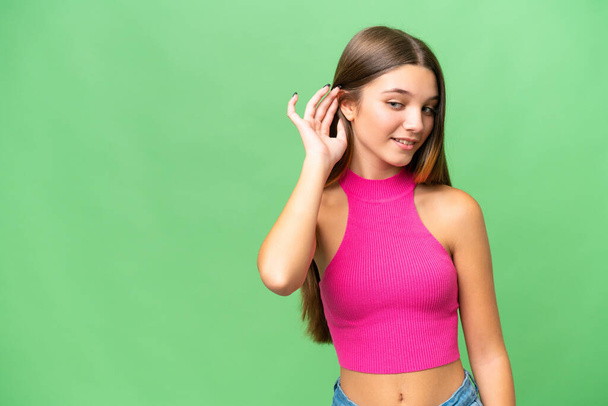 adolescent caucasien fille sur isolé fond écoute quelque chose en mettant la main sur l 'oreille - Photo, image