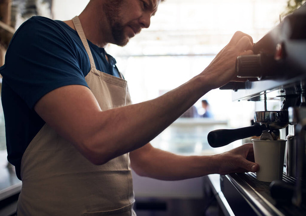 A tökéletes keverék összerakásának művészete. egy kávéfőzőt működtető barista egy kávézóban - Fotó, kép