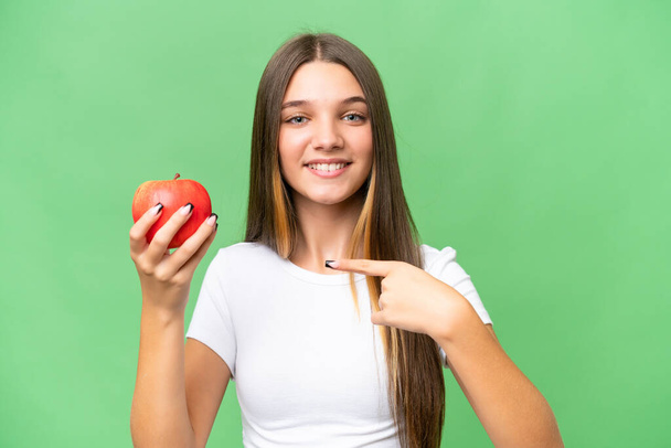 adolescent caucasien fille tenant une pomme sur isolé fond et pointant il - Photo, image
