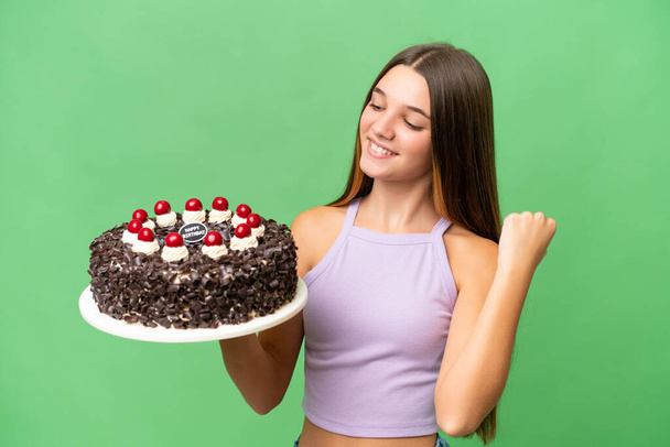 Teenager caucasian girl holding birthday cake over isolated background celebrating a victory - Fotó, kép