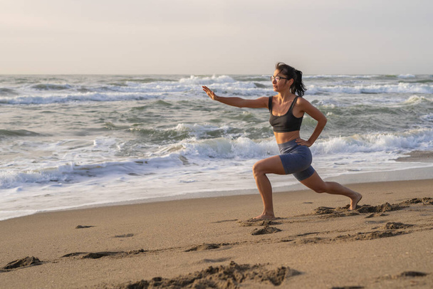 beautiful young girl is engaged in fitness on the beach doing lu - Φωτογραφία, εικόνα