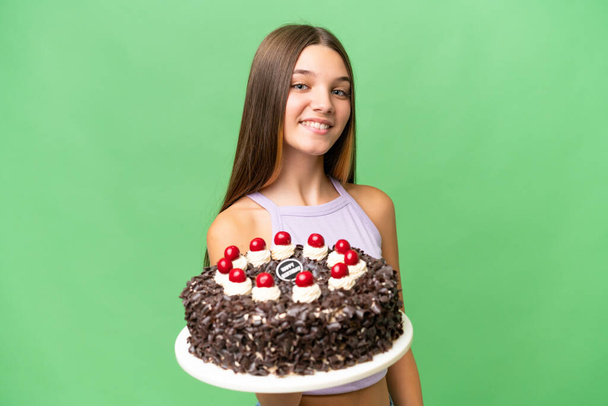 tiener Kaukasisch meisje holding verjaardag taart over geïsoleerde achtergrond met gelukkige expressie - Foto, afbeelding