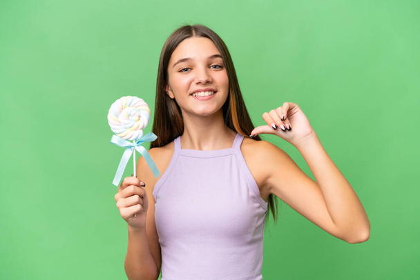 Adolescente caucásico chica sosteniendo una piruleta sobre aislado fondo orgulloso y auto-satisfecho - Foto, Imagen