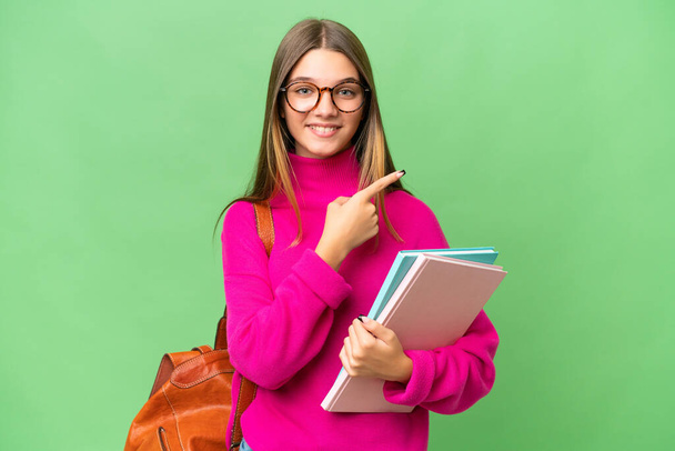 Adolescente estudante caucasiana sobre fundo isolado apontando para o lado para apresentar um produto - Foto, Imagem