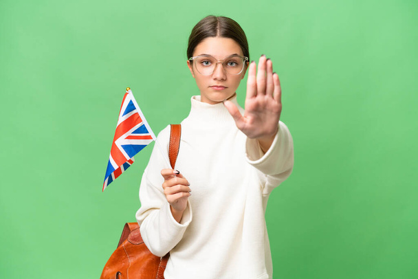 tinédzser diák kaukázusi lány gazdaság egy Egyesült Királyság zászló felett elszigetelt háttér így stop gesztus - Fotó, kép