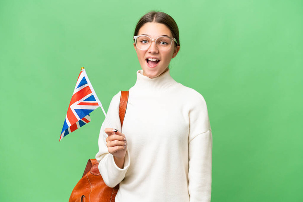 Teenager Student kaukasische Mädchen mit einer britischen Flagge über isoliertem Hintergrund mit überraschendem Gesichtsausdruck - Foto, Bild