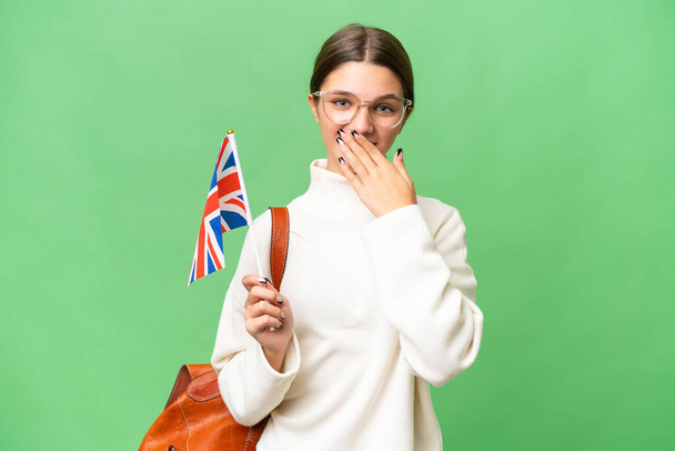 tinédzser diák kaukázusi lány gazdaság egy Egyesült Királyság zászló felett elszigetelt háttér boldog és mosolygós fedő száj kézzel - Fotó, kép