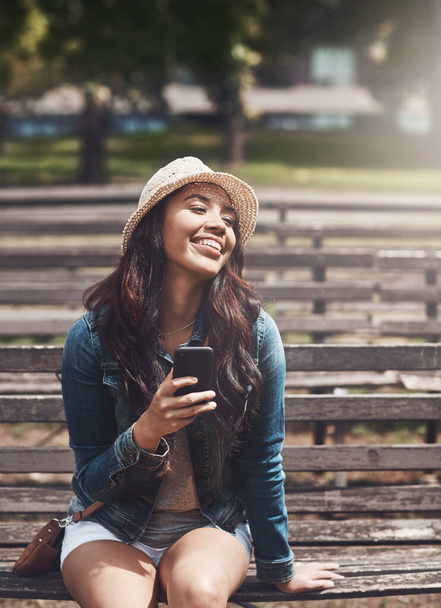 Gotta soak up these carefree days. an attractive young woman using a cellphone at the park - Foto, Imagen