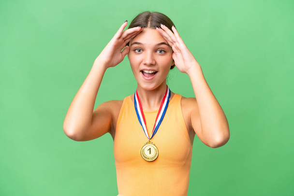 Adolescente caucasienne avec des médailles sur fond isolé avec expression surprise - Photo, image