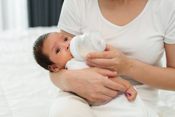 mother feeding milk bottle to her newborn baby on a bed - Valokuva, kuva