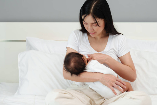 mother breastfeeding newborm baby on a bed - Фото, зображення