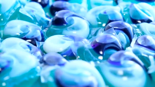 Kapsułki do mycia niebieskiego koloru, obracające się w kółko. Środki chemiczne do prania odzieży i bielizny - Materiał filmowy, wideo