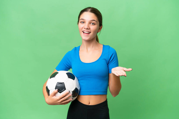 Teenager caucasian girl playing football over isolated background with shocked facial expression - Photo, Image