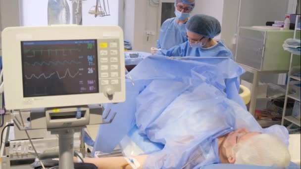 Los cirujanos operan en las piernas de una mujer mayor con venas varicosas. El proceso de trabajo de los cirujanos - Metraje, vídeo