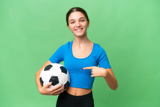 Teenager caucasian girl playing football over isolated background and pointing it - Photo, Image