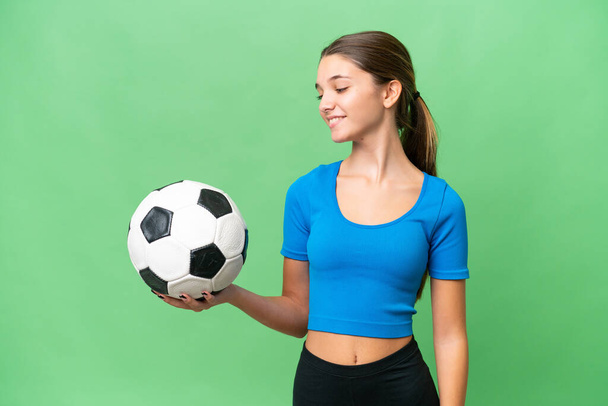 Teenager caucasian girl playing football over isolated background with happy expression - Photo, image