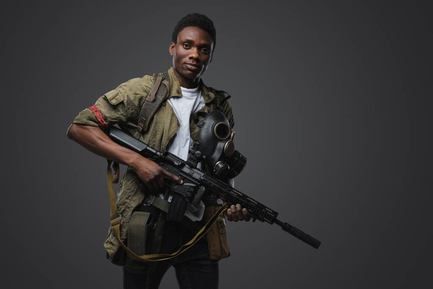 Shot of black soldier in post apocalyptic setting dressed in uniform and holding rifle. - Foto, afbeelding