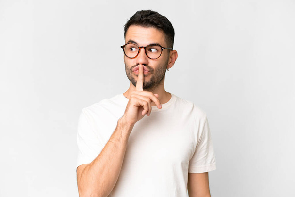 Young handsome caucasian man over isolated white background showing a sign of silence gesture putting finger in mouth - Foto, Imagem
