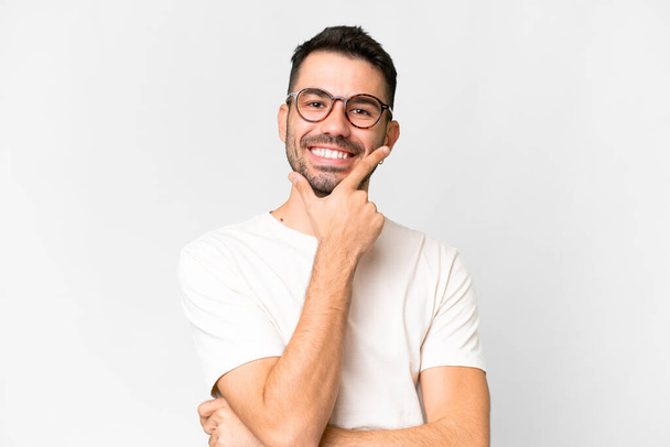 Jonge knappe blanke man over geïsoleerde witte achtergrond gelukkig en glimlachend - Foto, afbeelding