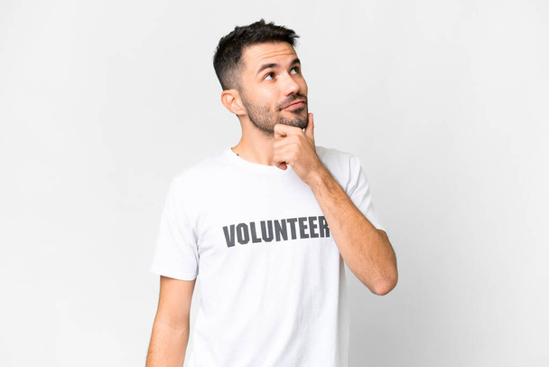Young volunteer caucasian man over isolated white background having doubts - Photo, Image