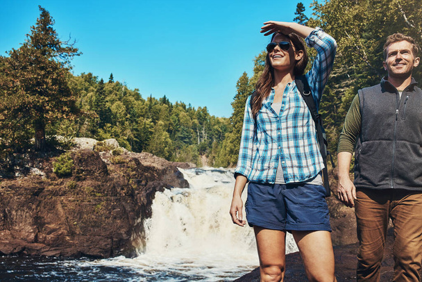 Nature aka home. a young couple walking next to a rocky river and waterfall - Photo, Image