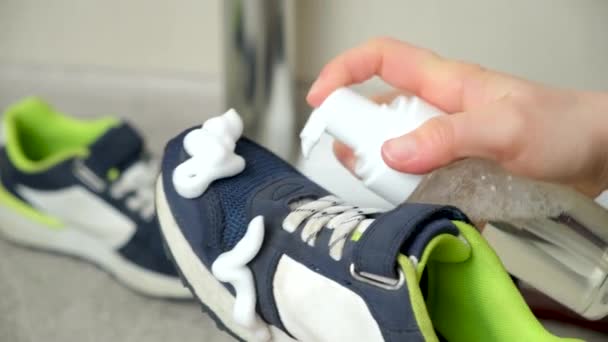 La aplicación de espuma de limpieza de la botella a los niñoszapatillas de deporte de tela azul. Cuidado de los zapatos, limpieza de polvo y suciedad. - Imágenes, Vídeo