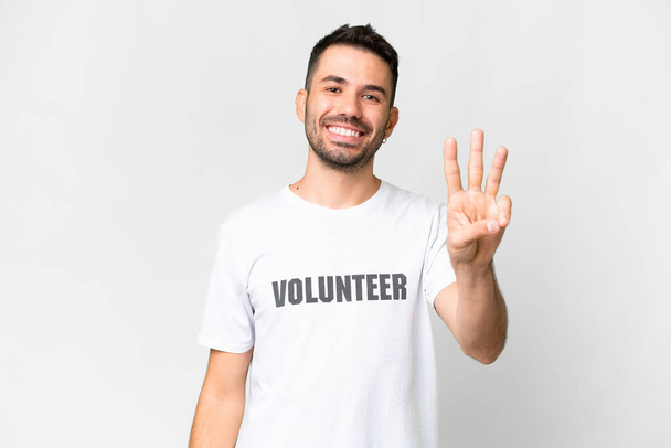 Молодий волонтер білий чоловік над ізольованим білим тлом щасливий і рахуючи трьох пальцями
 - Фото, зображення
