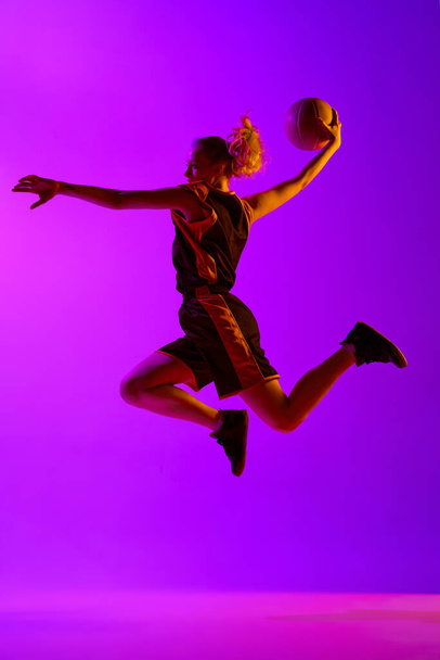 Full-length dynamical image of young female basketball player, girl training with ball against white studio background. Concept of professional sport, hobby, healthy lifestyle, action and motion - Foto, imagen