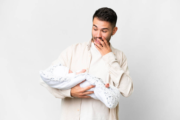 Jeune père caucasien avec son nouveau-né sur fond isolé avec une expression faciale surprise et choquée - Photo, image