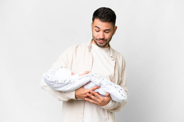 Joven padre caucásico con su bebé recién nacido sobre un fondo aislado con expresión triste - Foto, imagen