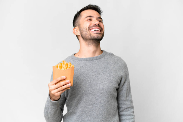 Fiatal fehér férfi kezében sült chips felett elszigetelt fehér háttér nevetés - Fotó, kép