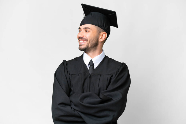 młody absolwent uniwersytetu człowiek na odizolowanym białym tle szczęśliwy i uśmiechnięty - Zdjęcie, obraz