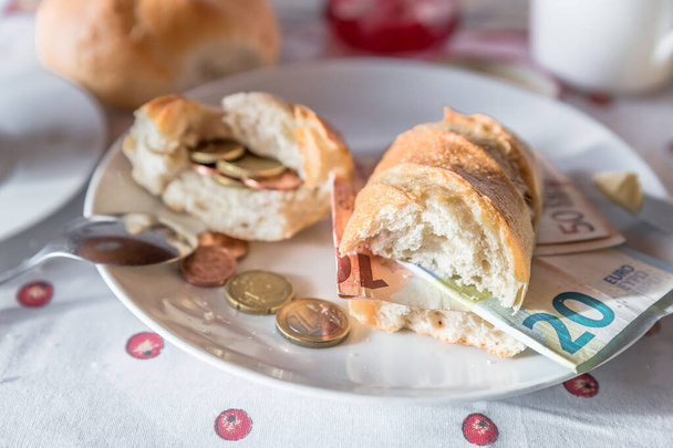 Conjunto de mesa de desayuno con desayuno de leche y mantequilla de azúcar de café y rollo cubierto con monedas y billetes de euro en el plato, Alemania - Foto, imagen