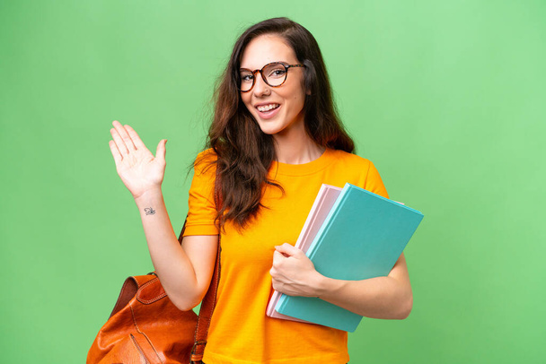 Young student caucasian woman over isolated background saluting with hand with happy expression - Photo, image