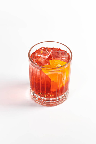 Rode zoetzure cocktail versierd met een sinaasappelschijfje. Op een witte geïsoleerde achtergrond. - Foto, afbeelding