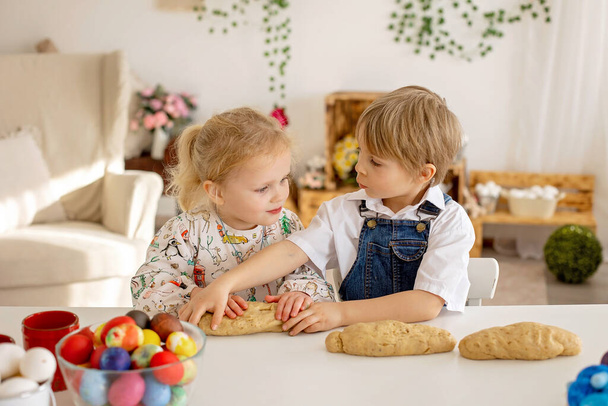 Little blond toddler boy child with sister, preparing dough for easter brioche buns, sweet easter bread with nuts and dry fruits at home - Fotoğraf, Görsel