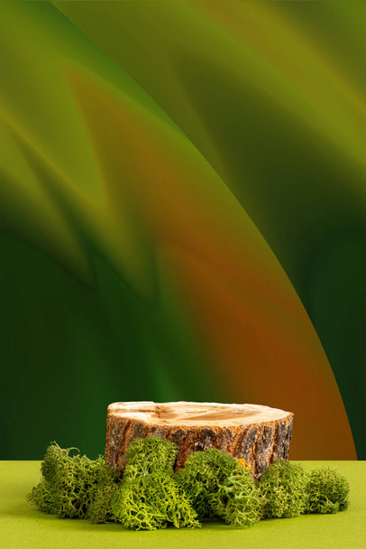  Ξύλινο πριόνι κομμένο, στρογγυλό βάθρο με πράσινα βρύα. Νεκρή φύση για την παρουσίαση των προϊόντων. Φάντασι πράσινο-πορτοκαλί αφηρημένο φόντο - Φωτογραφία, εικόνα