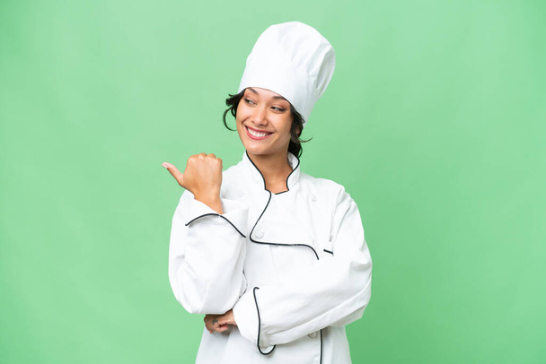 Giovane chef donna argentina su sfondo isolato che punta verso il lato per presentare un prodotto - Foto, immagini