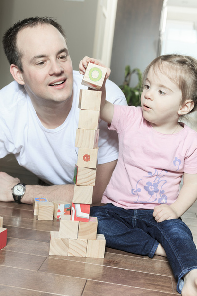 Relaxed father and daughter playing with building blocks on wood - Fotografie, Obrázek