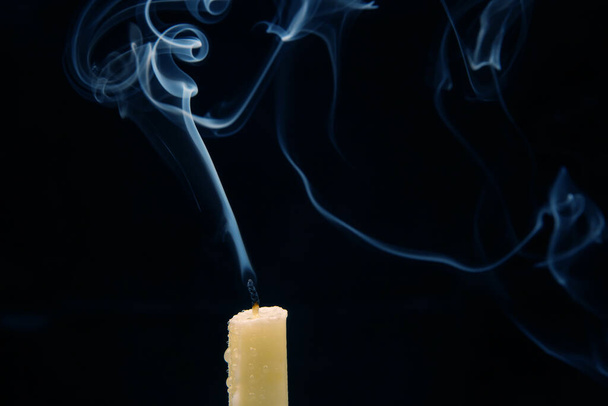 Smoke from an extinguished candle on a dark background. The concept of spirituality and the end of life. - 写真・画像