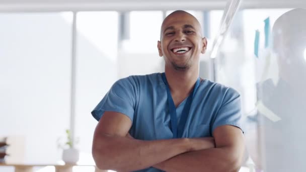 Šťastný, sebevědomý a tvář lékaře v jeho kanceláři po konzultaci v nemocnici. Štěstí, úsměv a portrét mužského zdravotnického pracovníka stojícího se zkříženýma rukama na lékařské klinice - Záběry, video
