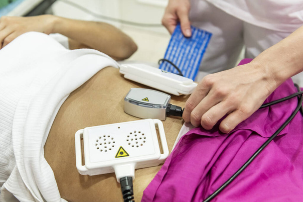 Aplikace přístrojů ze stroje pro aplikaci dermo-estetické léčby na záda pacienta na klinice - Fotografie, Obrázek