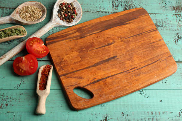 Different spices and herbs with cutting board on color wooden table background - Foto, afbeelding