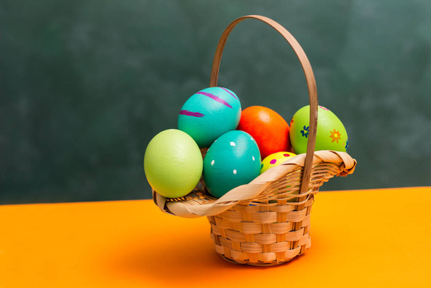 Wiklinowy koszyk wielkanocny z kolorowymi jajkami - Zdjęcie, obraz