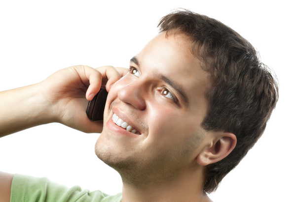 Улыбающийся молодой человек разговаривает по мобильному телефону изолированному на белом
 - Фото, изображение