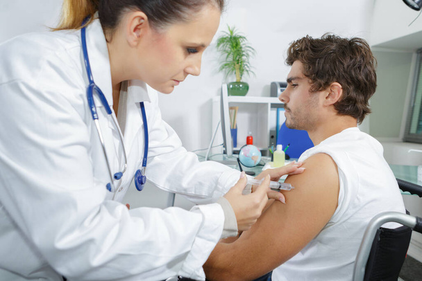 physiotherapist injecting male patient in clinic - Photo, image