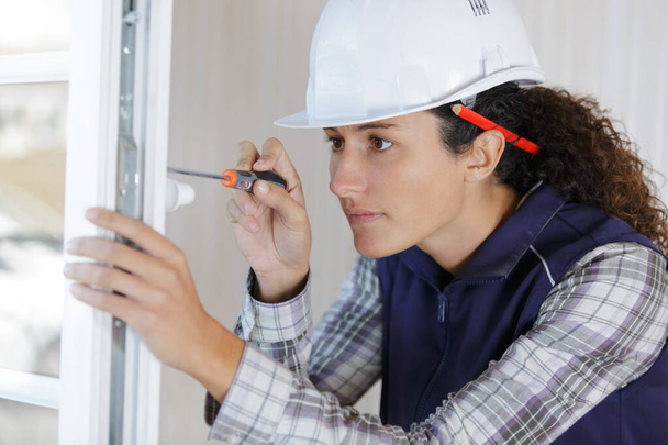 female builder fitting a window - Foto, immagini