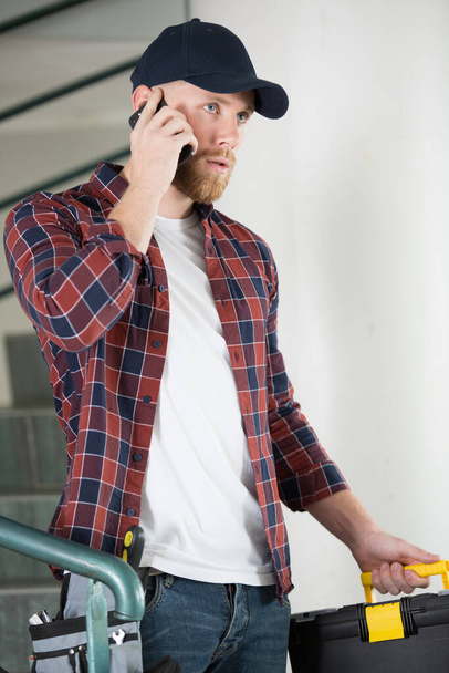 electrician using cellphone while talking to customer - Φωτογραφία, εικόνα