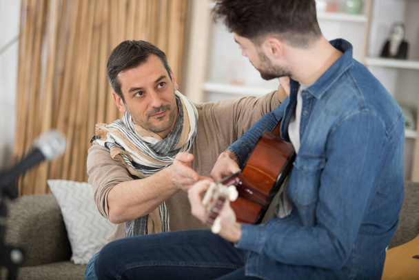 young man having a guitar lesson at home - Fotó, kép