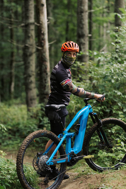 Mountain bike cyclist in sport equipment and helmet riding on rugged trails. - 写真・画像